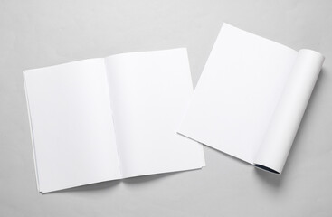 Mockup of two open magazines with white open pages on a gray background. Template for design