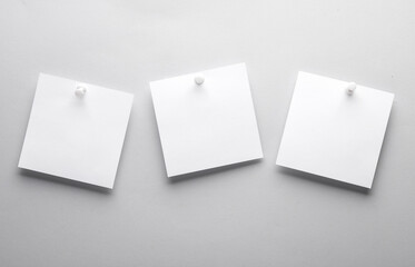 White empty square memo sheets of paper with pushpin on gray background. Template for design.