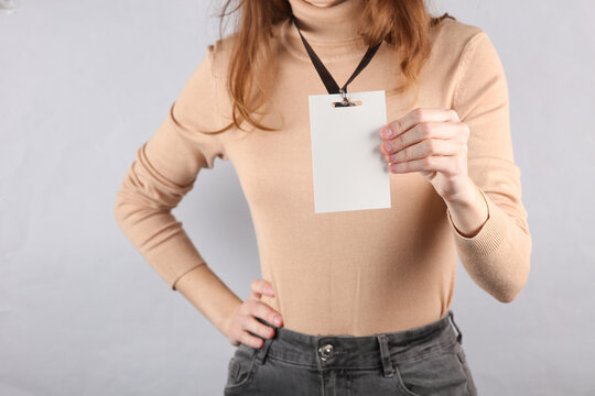 Young woman wearing Identification white blank id card on gray background