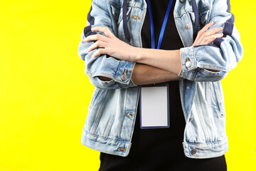 Young woman wearing blank id card on yellow bvackground