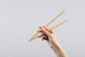 Chinese chopsticks in a female hand on a gray background