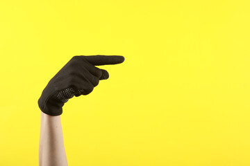Female hand in working fabric glove shows finger on space for text, against yellow background
