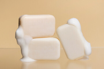 Pieces of light soap with foam on a beige isolated background. Natural cosmetics for skin care...