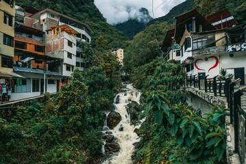 River flowing in Aguas Calientes, Peru surrounded by lush greenery and residential buildings