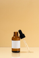 Brown mockup glass jar of serum with dropper on beige isolated background. Concept of cosmetology and natural skin care products. Image for your design.