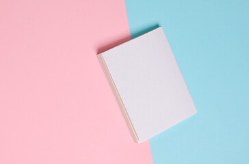 Book or notepad mockup with white cover on pink blue background. Template for design