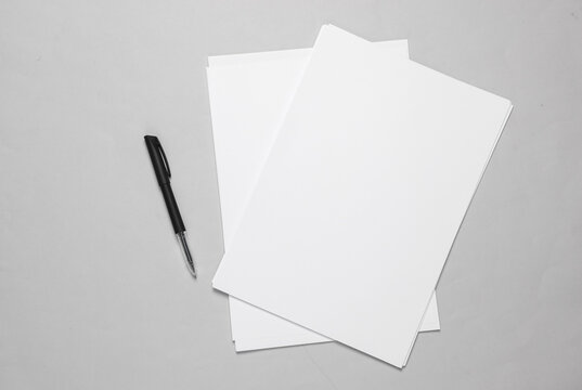 White blank sheets of a4 paper size or documents mockup with pen on a gray background. Template for design