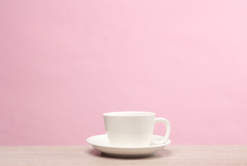 Ceramic white coffee cup on the table, pink background