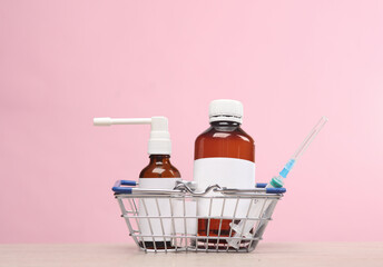 Medicines with blank labels in supermarket basket on a pink background. Template for design