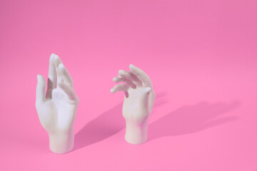 White plastic hands on a pink background. Minimal layout