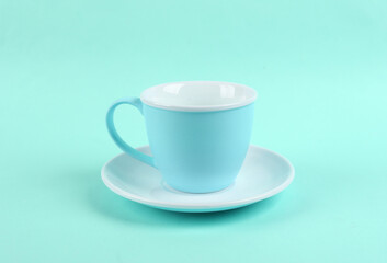 Empty ceramic cup and saucer on blue background