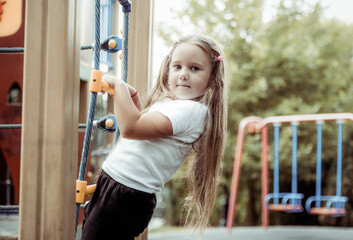 Little active girl spends time on the playground outdoor