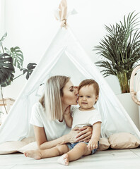 Young mother and little daughter spend time together in a wigwam at home © splitov27