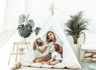 Happy woman mom and her little daughter playing in wigwam at home © splitov27