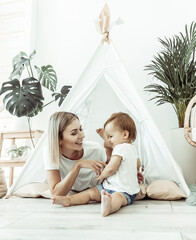 Young mother and little daughter spend time together in a wigwam at home © splitov27