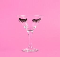 Cocktail glass with eyelashes on pink background. Fresh idea. Minimal easter concept, creative layout