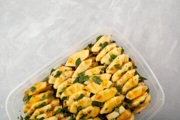 Traditional Asian fruit salad. Fermented Pineapple slices with mint leaf in cane sugar syrup. Sweet Pineapple dessert in plastic container on grey background. Selective focus, copy space.
