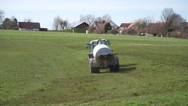 Agricultural tractor waters and fertilizes the grass field with natural fertilizer.