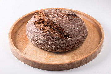 Fresh round black bread with a crispy crust. Close-up on a white background