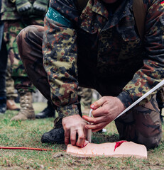 Soldier trains to stop bleeding from a gunshot wound using tamponade on a bullet wound simulator.
