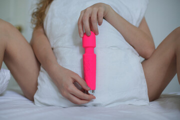 Young happy sexy woman hold in hand sex toy, masturbate with vibrator in bed in bedroom at home.