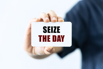 Seize the day text on blank business card being held by a woman's hand with blurred background....