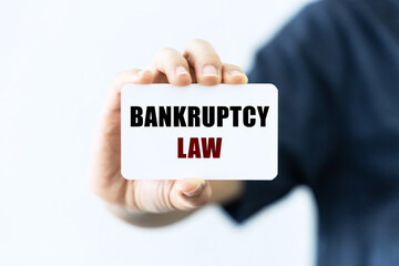 Bankruptcy law text on blank business card being held by a woman's hand with blurred background. Business concept about Bankruptcy law.