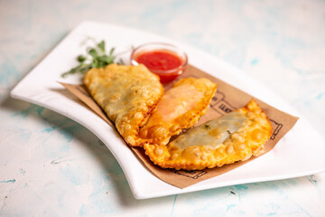 fried delicious chebureks with sauce on a white plate