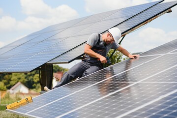 Male engineer in protective helmet installing solar photovoltaic panel system. Alternative energy ecological concept. © Serhii