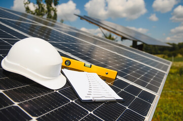 Solar cell contractor document with orange engineering team helmet on solar cells panels. Renewable...