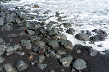 Fototapeta na wymiar Polished Volcanic Rocks in a Foamy Ocean Wave