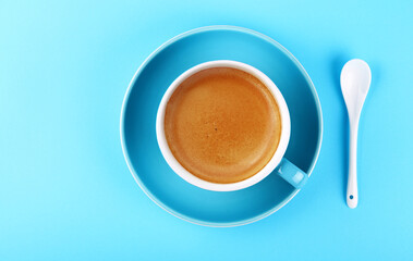 Full cup of espresso coffee on blue paper