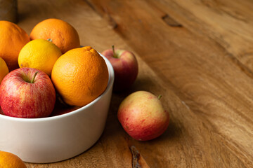 Fototapeta na wymiar Vibrant warm bright coloured (red, orange, yellow) background with fruit and a vintage rustic wooden table with copy space. Fruit as an immune booster helps during flu and other illnesses
