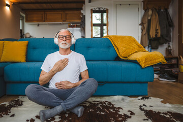 Obraz premium One senior man doing guided meditation yoga self care practice at home
