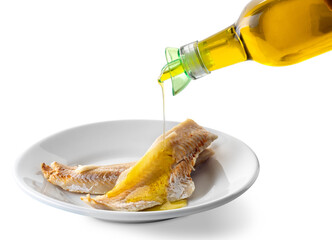 Cod fillet in white dish with extra virgin olive oil poured from bottle with drip cap. Isolated