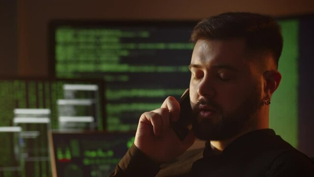 Close-up shot of a freelance programmer talking on the phone. A web programmer is discussing the development of a website with a customer over the phone.