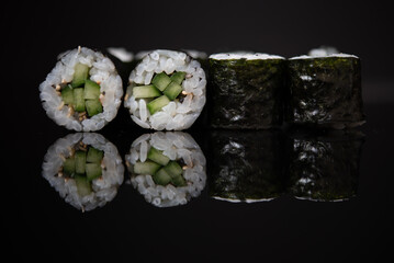 Assorted sushi rolls with salmon tuna cucumber and sesame seeds on dark background © Lemonade