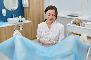 Doctor preparing for gynecological examination of young woman on chair