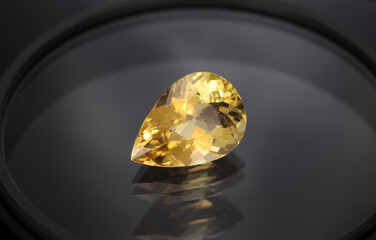 Golden yellow color natural heliodor beryl drop shaped loose faceted gemstone setting. Clean, transparent unheated genuine stone for making jewelry. Multiple reflection on glass surface. Gemology.