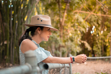 portrait of young adult woman wearing hat leaning on a railing in a tropical landscape.