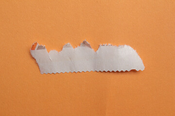 Ripped newspaper piece isolated on a orange background
