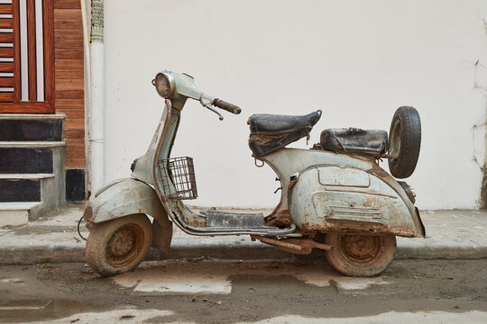 Delhi, India - old dusty rusty motor scooter parked at a curb