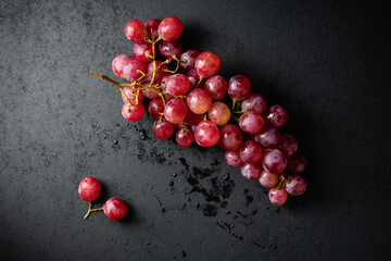 Branch of red grapes on a dark background.