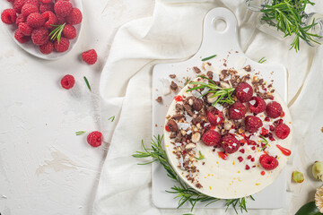 Cheesecake with raspberries, chocolate, hazelnuts and rosemary leaves on kitchen coutertop