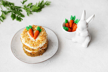 Easter Carrot cake with cream cheese frosting and marzipan decorations on a white stone background...