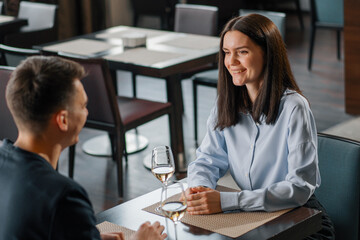 A date in a hotel restaurant a man and a woman drink white wine in glasses the face of a smiling girl