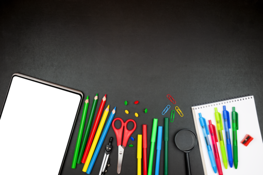 Digital tablet with blank transparent screen and bright school supplies on blackboard background. Top view with copy space