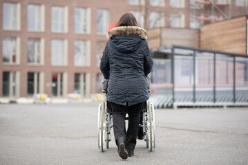 A woman pushes a disabled person in a wheelchair