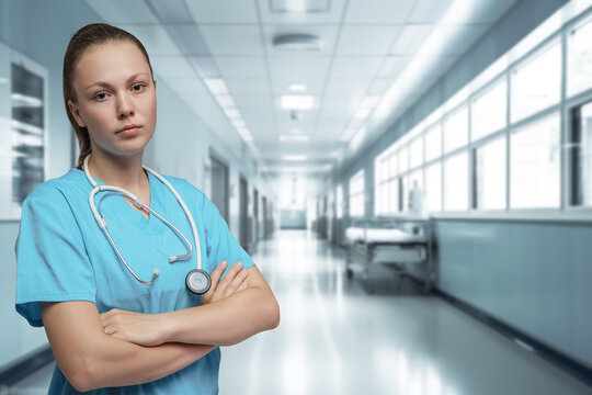 Shot of professional nurse with blue robe posing with crossed arms in hospital.