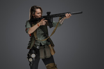 Portrait of military woman with rifle looking to side isolated on grey background.